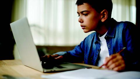 Kid using laptop and writing notes